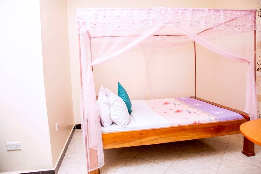 A single bed with a wooden frame and a canopy, accompanied by a bedside table.