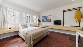 Un dormitorio moderno con una cama grande, suelo de madera, televisor empotrado y un cuadro en la pared.