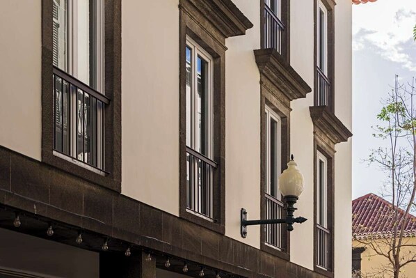 Une façade d’immeuble avec de grandes fenêtres, un lampadaire et un arbre en arrière-plan.