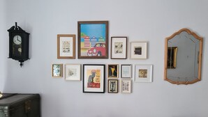 A living room with a brown sofa, a vintage clock, and various framed artworks on the wall. - 1930 NINETEEN THIRTY (Gijón)