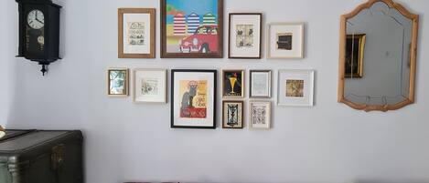 Una pared decorada con varios cuadros enmarcados, un reloj y un espejo.