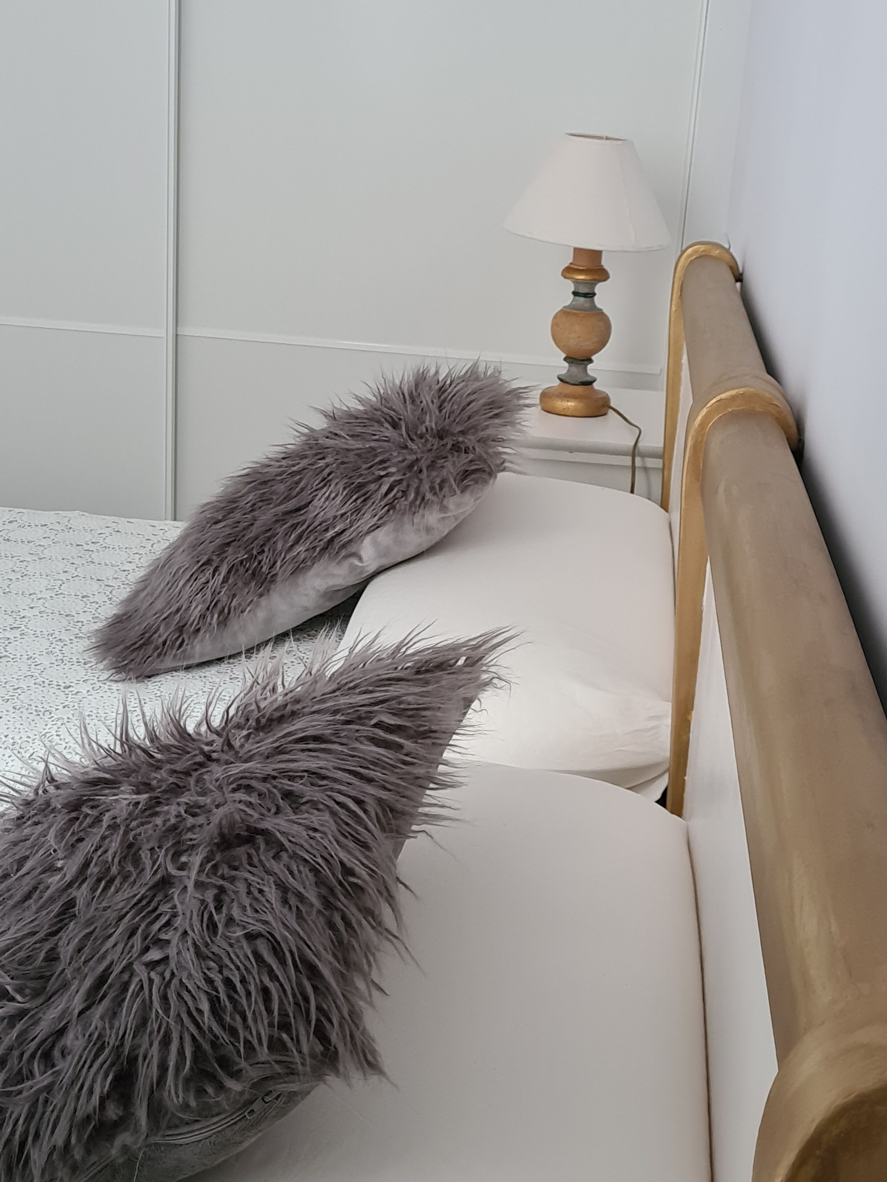 Una cama con cabecera de madera, dos almohadas y una lámpara de noche.