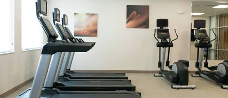 A fitness center with treadmills, elliptical machines, and stationary bikes.