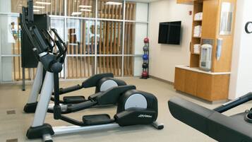 Un gimnasio con cintas de correr, un banco de pesas y un dispensador de agua.