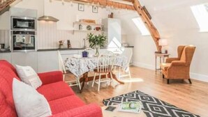 Un appartement confortable de style loft, comprenant un coin repas, une cuisine et un canapé rouge.