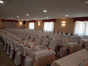 A banquet hall with rows of tables set for a formal event, each with white tablecloths, glassware, and folded napkins. - Complejo O Piñeiral (Fonsagrada)