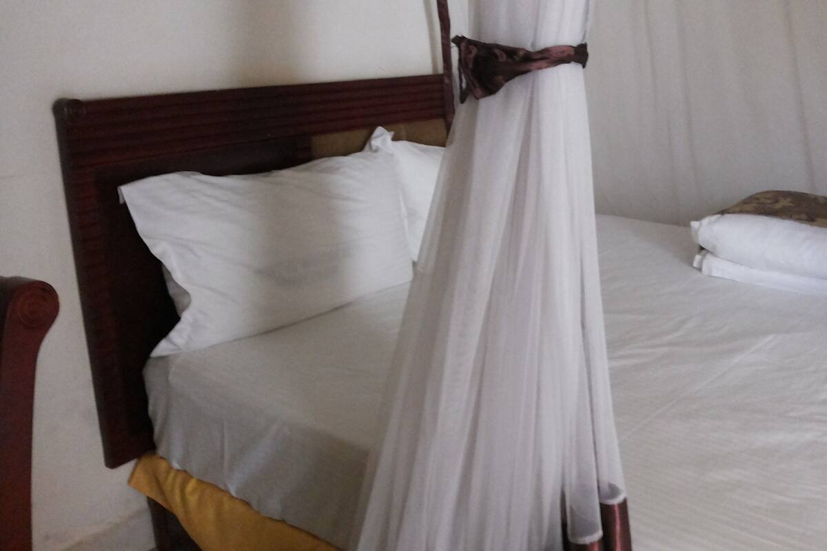 A bed with a canopy, a wooden headboard, and a white mattress.