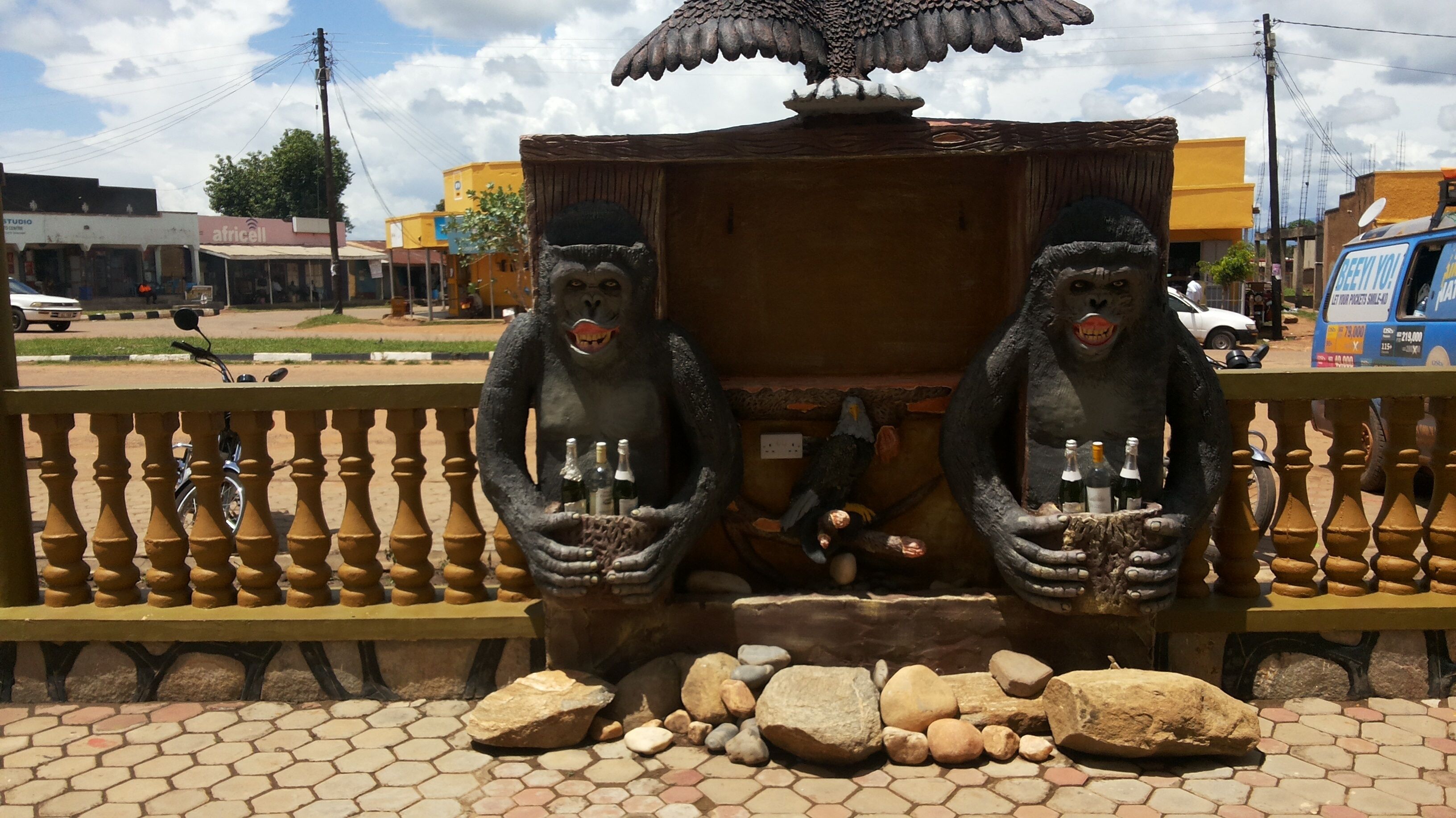 Una estructura decorativa con dos figuras sosteniendo botellas, rodeada por una barandilla y rocas.