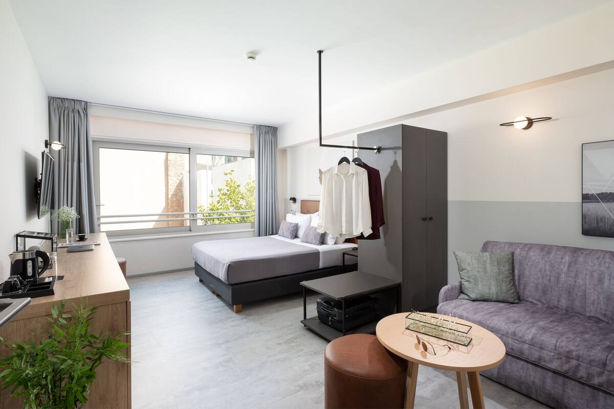Une chambre d’hôtel moderne équipée d’un lit, d’un bureau, d’un canapé et d’un balcon avec vue.