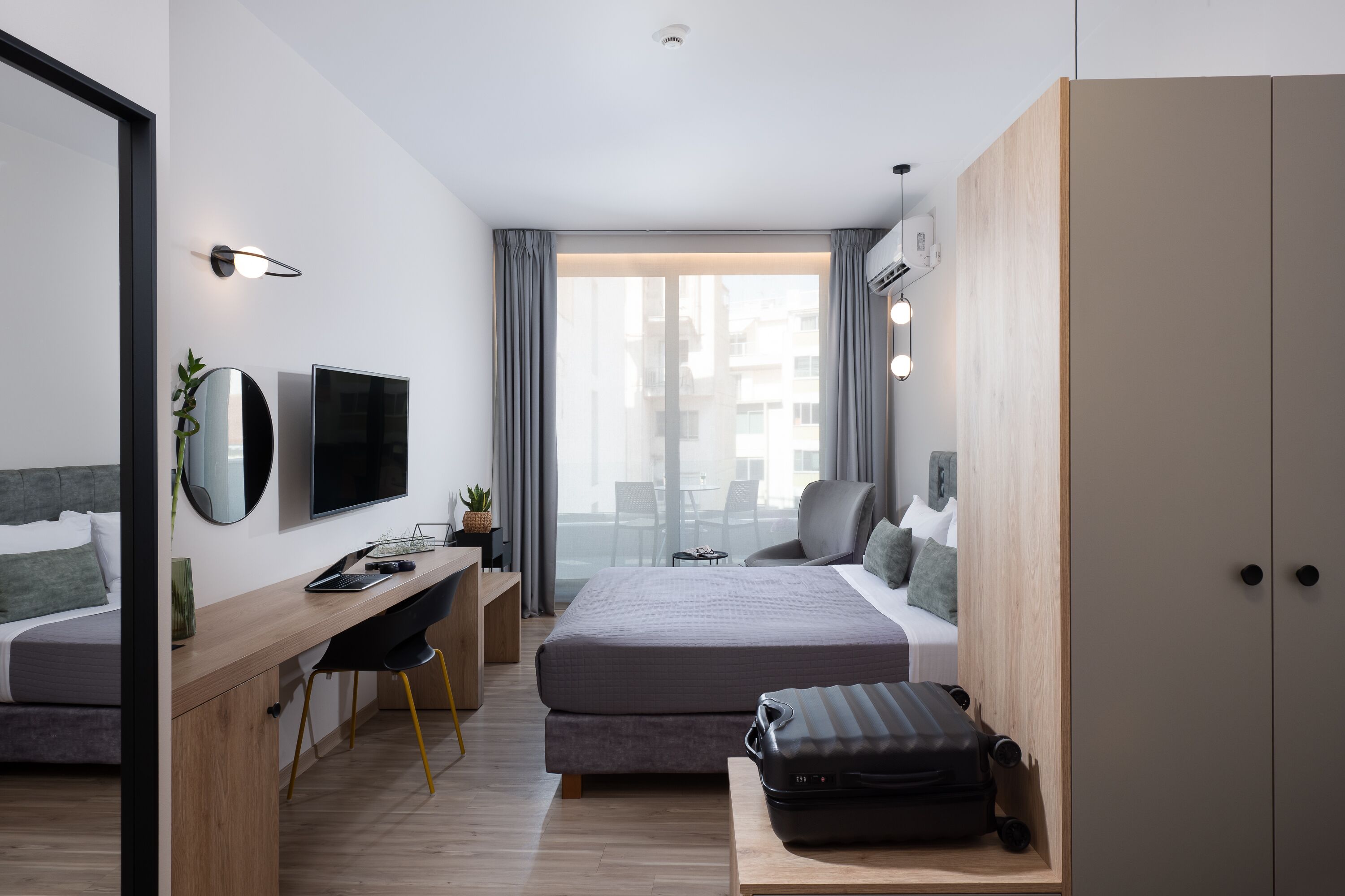 A modern hotel room with a bed, desk, and seating area.