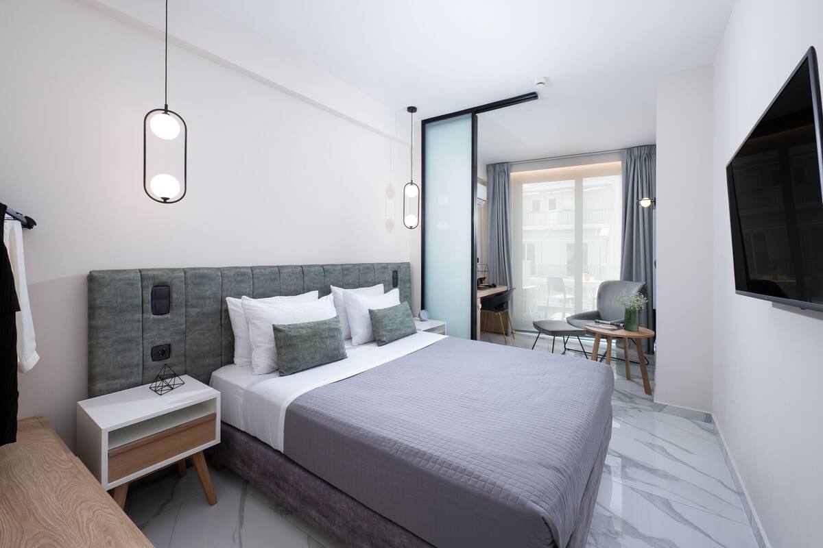 Une chambre d’hôtel moderne avec un grand lit, des tables de chevet, un bureau et une télévision.