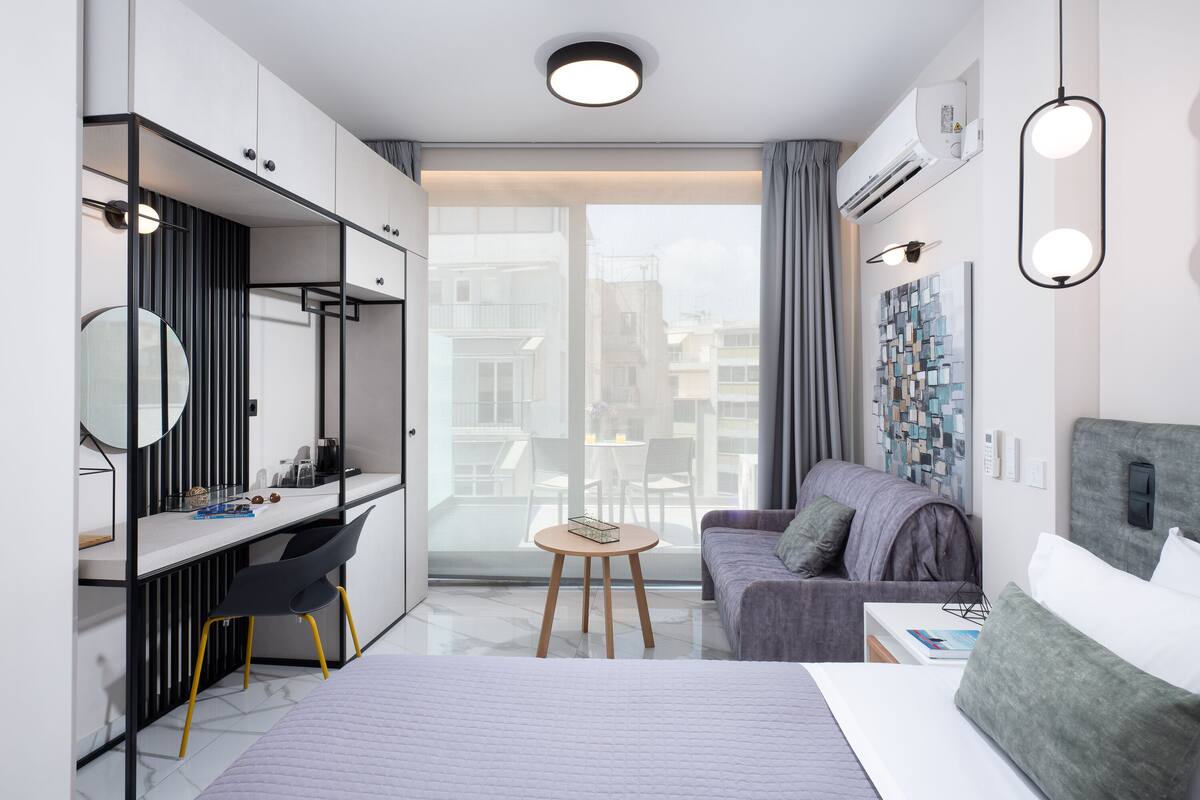 Une chambre d’hôtel moderne équipée d’un lit, d’un bureau, d’un canapé et d’une grande fenêtre.