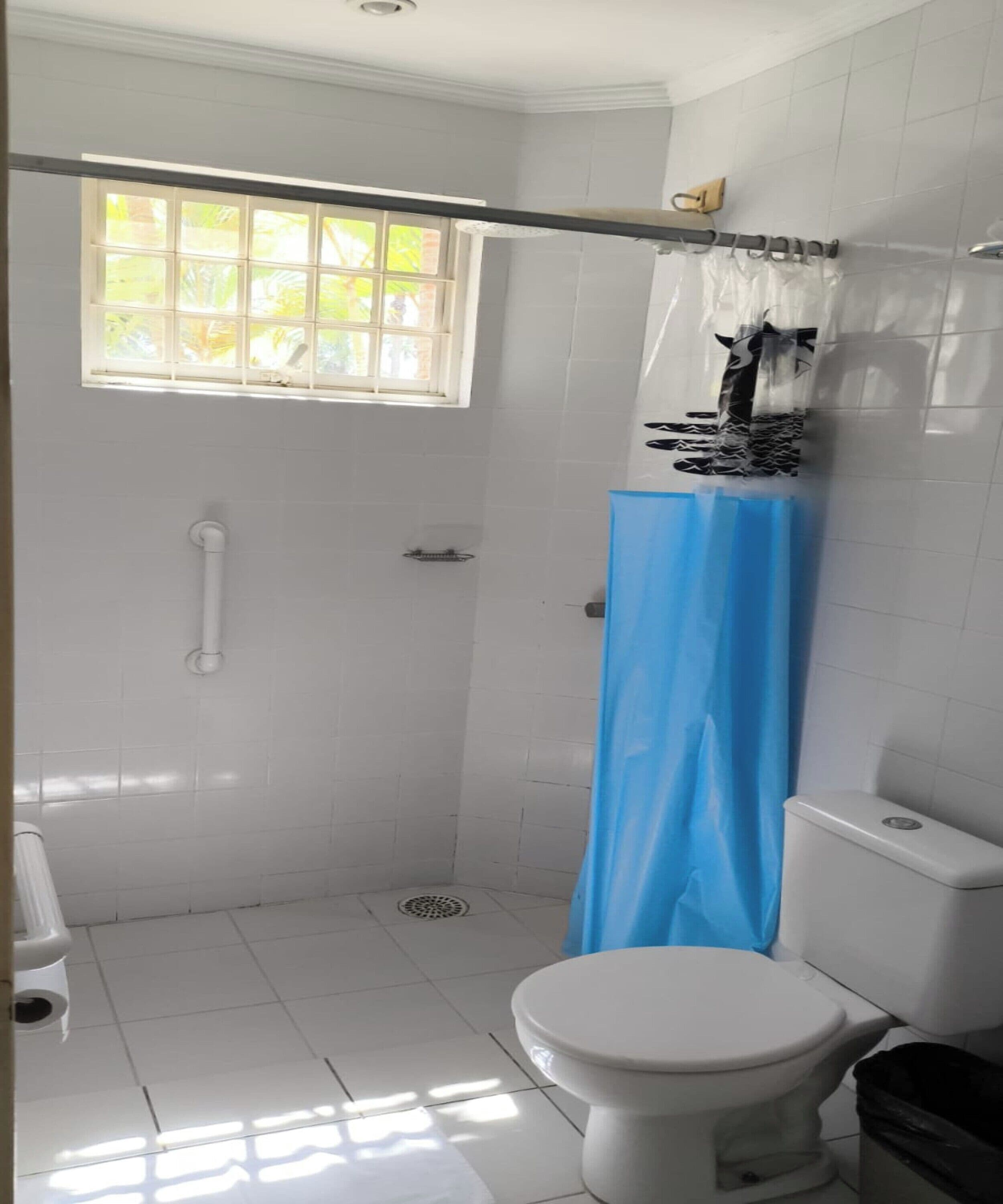 Un baño con inodoro, ducha y ventana.