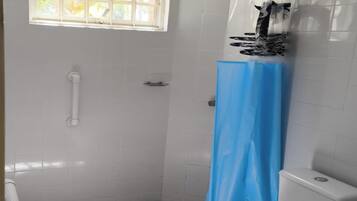 Un baño con inodoro, ducha y ventana.