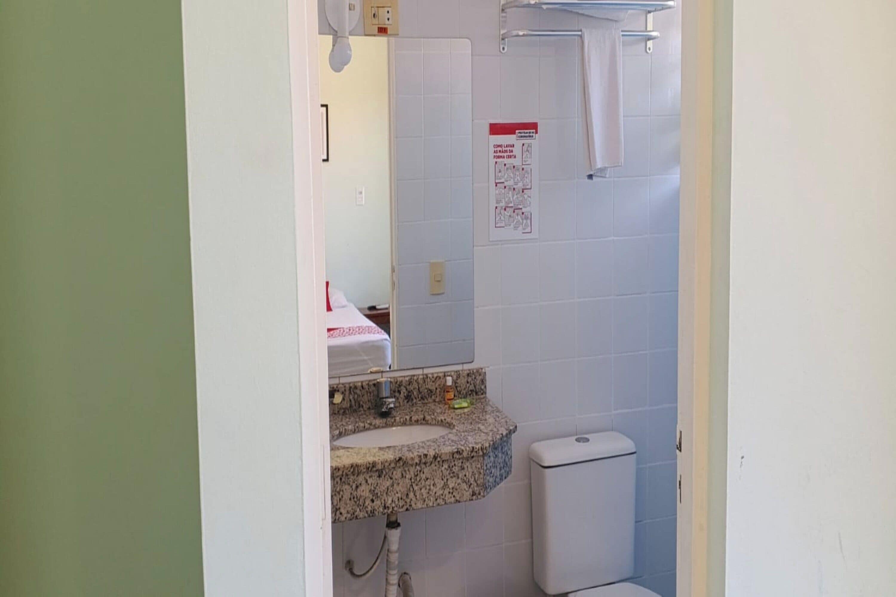 A bathroom with a granite sink, white toilet, and a towel hanging on a rack.