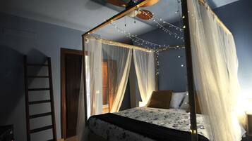 Ein Schlafzimmer mit Baldachinbett, Deckenventilator und Lichterkette.