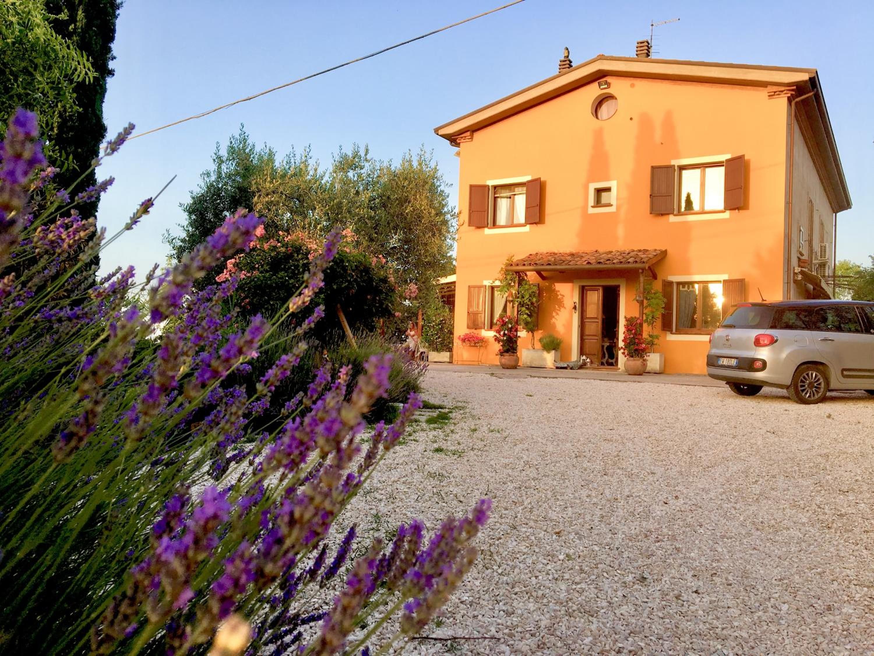 Un bâtiment à deux étages avec une allée gravillonnée et une voiture garée.