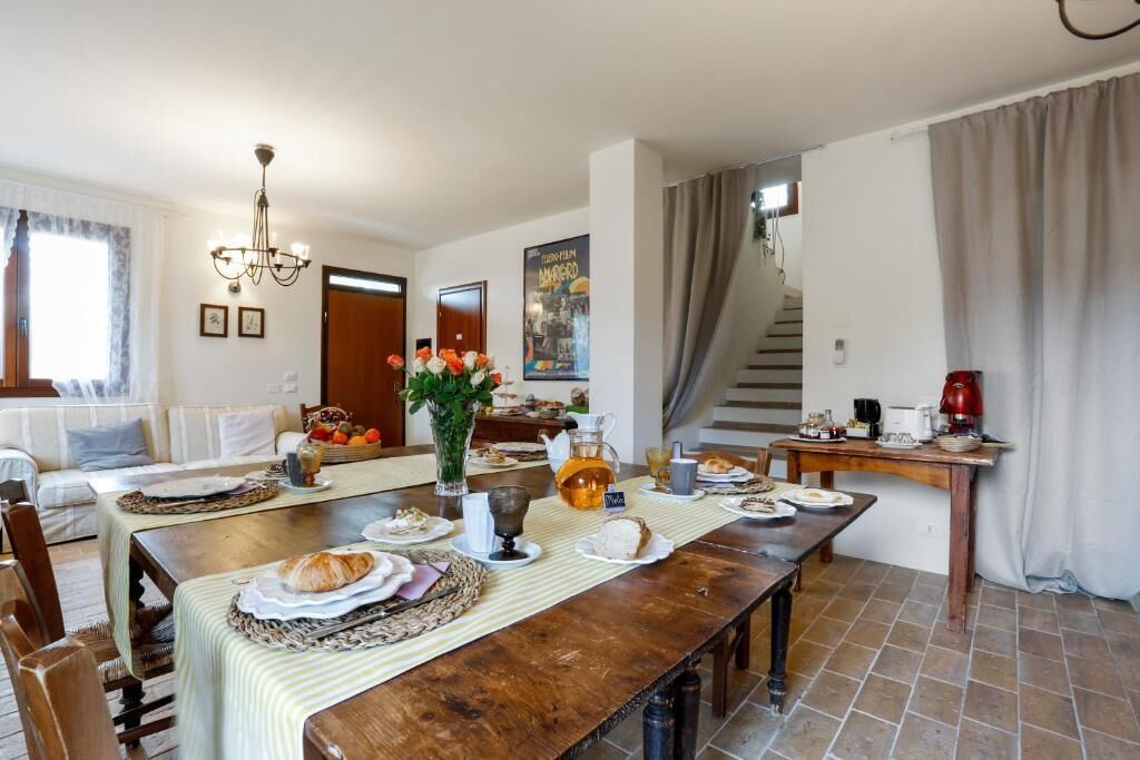 Un espace repas avec une table en bois dressée pour le repas, un lustre et un escalier menant à un autre niveau.