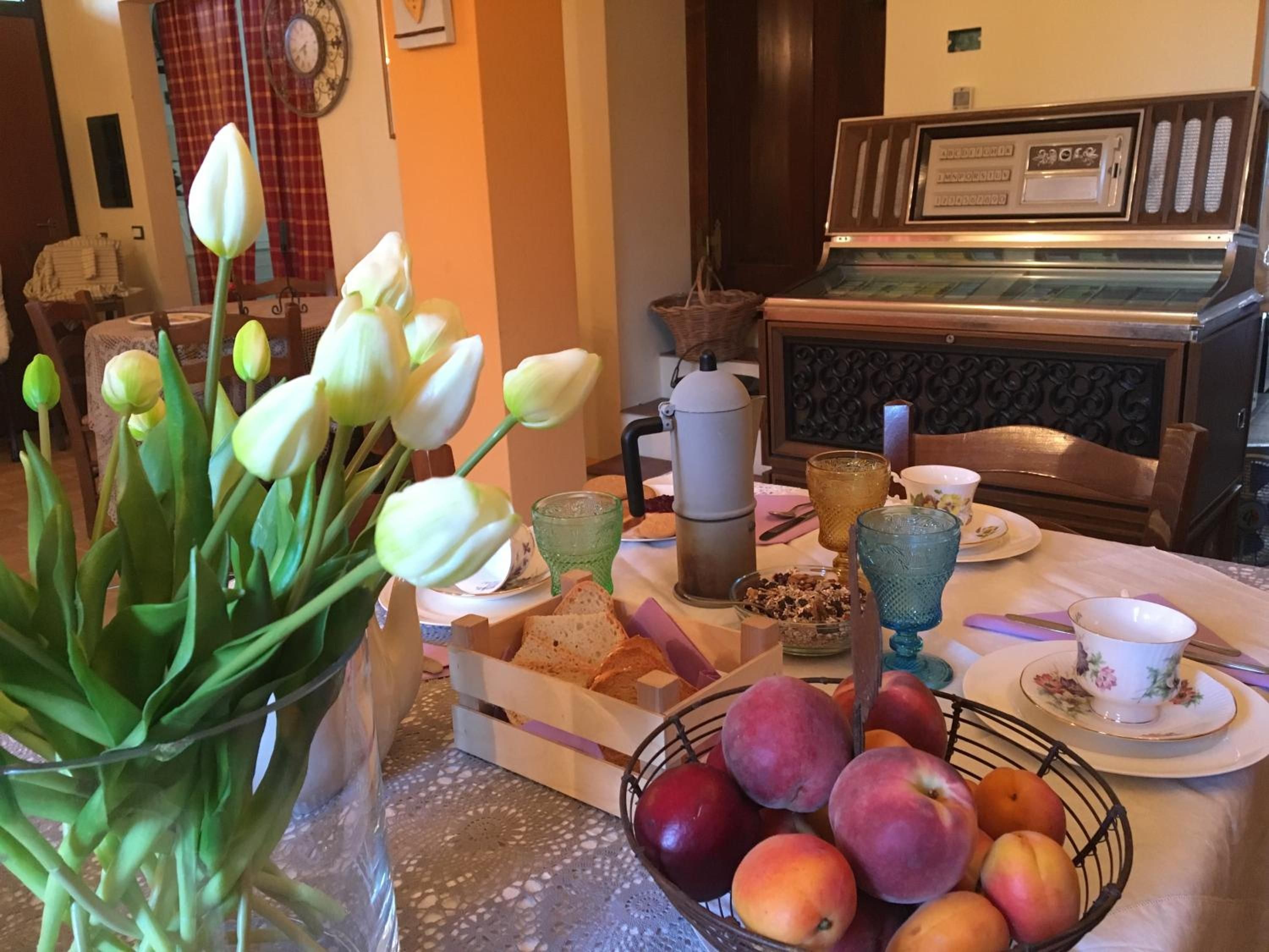 Ein Esstisch mit einer Tulpenvase, einem Obstkorb und einer Kaffeemaschine.