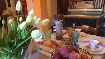 Ein Esstisch mit einer Tulpenvase, einem Obstkorb und einer Kaffeemaschine.