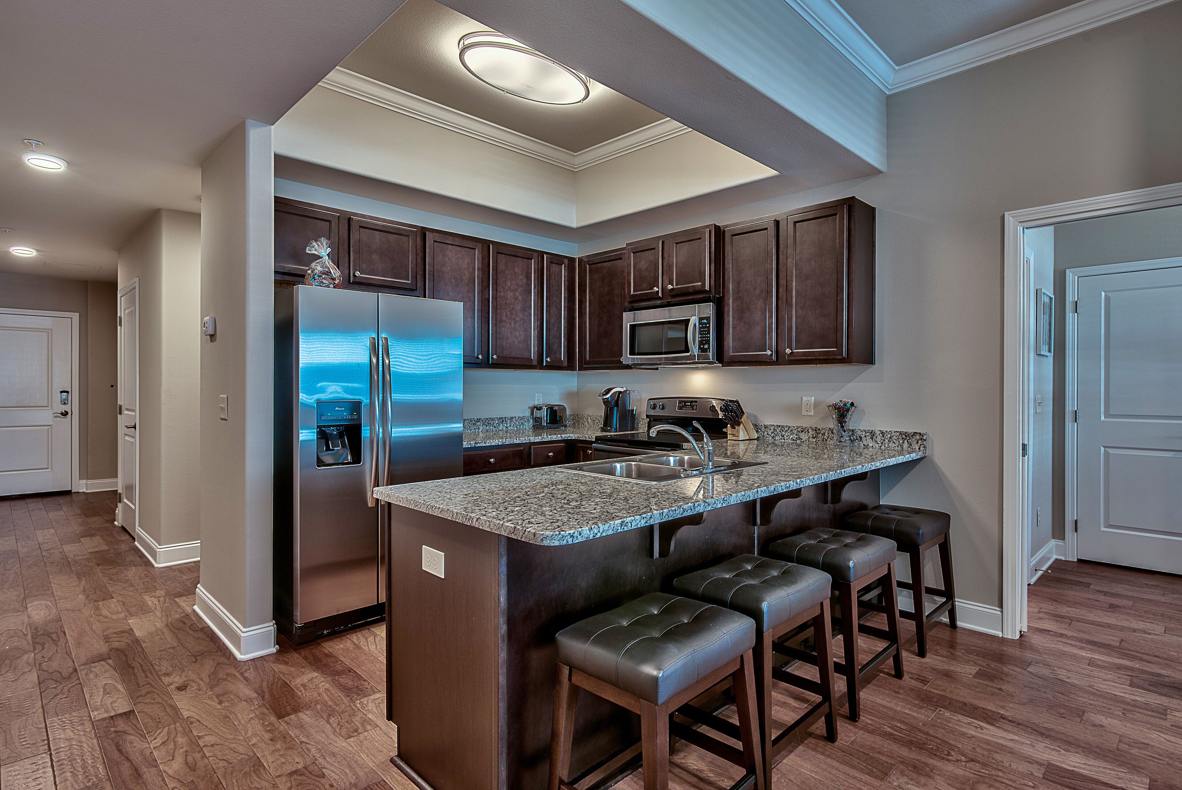 A modern kitchen with a central island, stainless steel appliances, and dark wood cabinetry.
