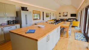 A spacious kitchen with a central island, a dining area with chairs, and a living room with a sofa. - The Cotswold Manor Court, Exclusive Hot Tub, Games Barn, 70 acres of Parkland (Bampton)