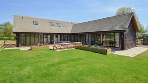 A modern building with a large patio area, a wooden deck, and a swimming pool. - The Cotswold Manor Court, Exclusive Hot Tub, Games Barn, 70 acres of Parkland (Bampton)