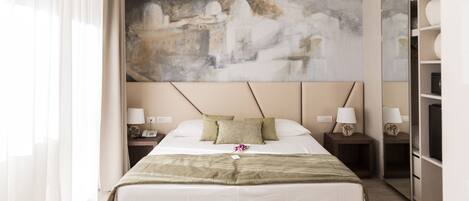 Habitación de hotel con una cama grande, dos mesitas de noche con lámparas, un cuadro abstracto grande en la pared y un armario con espejo.