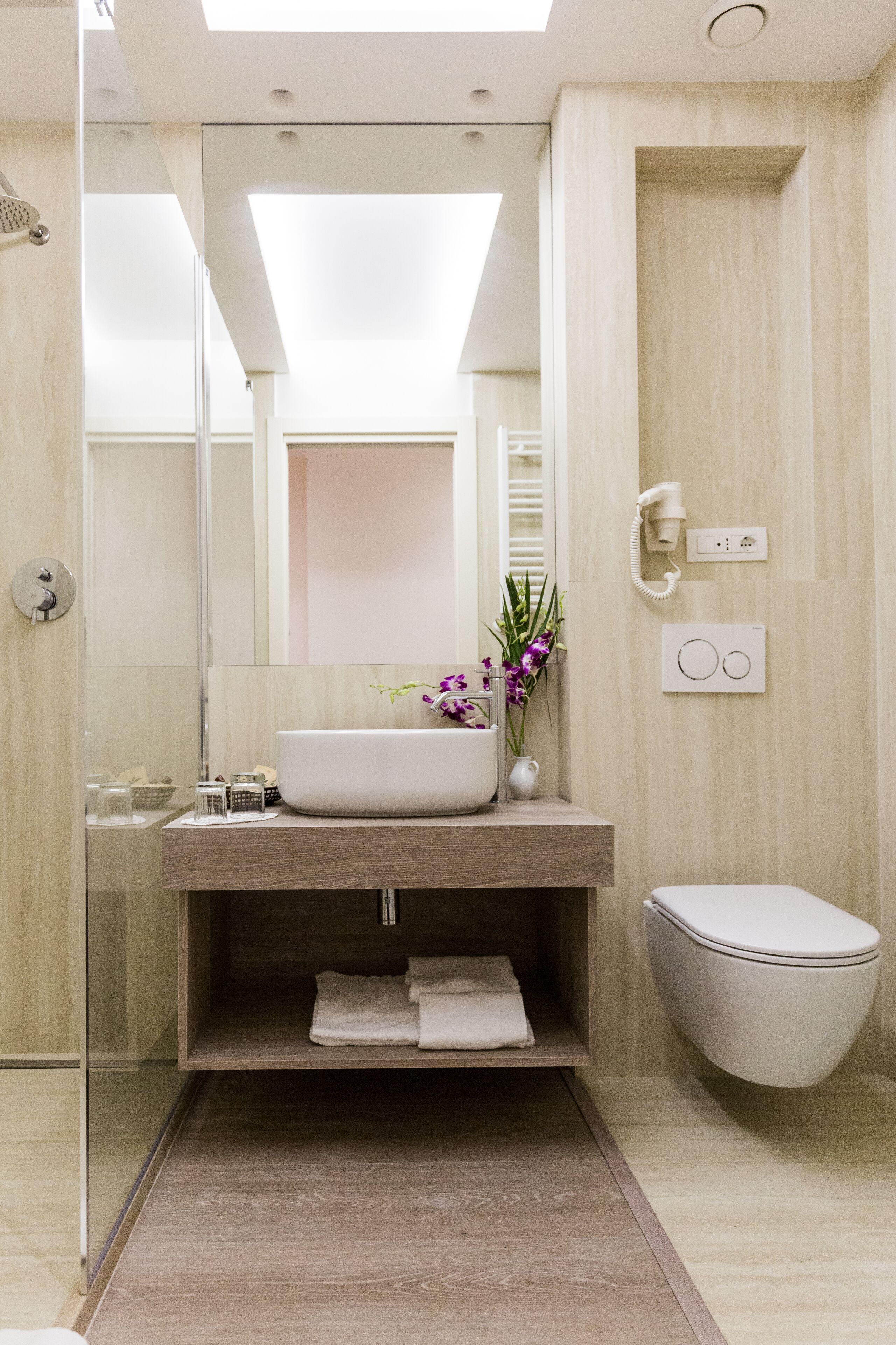 A modern bathroom with a large mirror, a sink, a toilet, and a shower area.