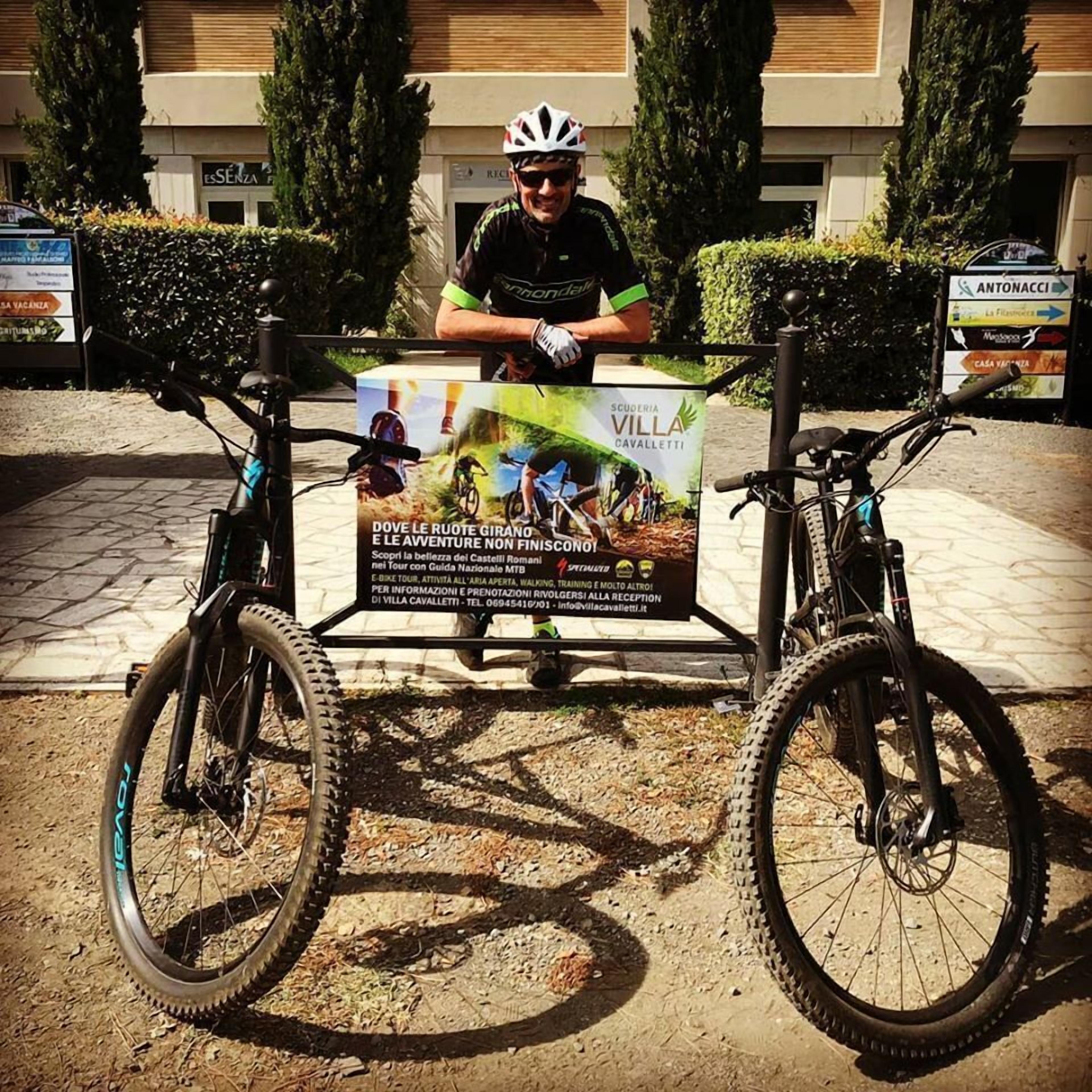 Pessoa em pé atrás de uma bicicleta com um letreiro indicando um evento ciclístico.