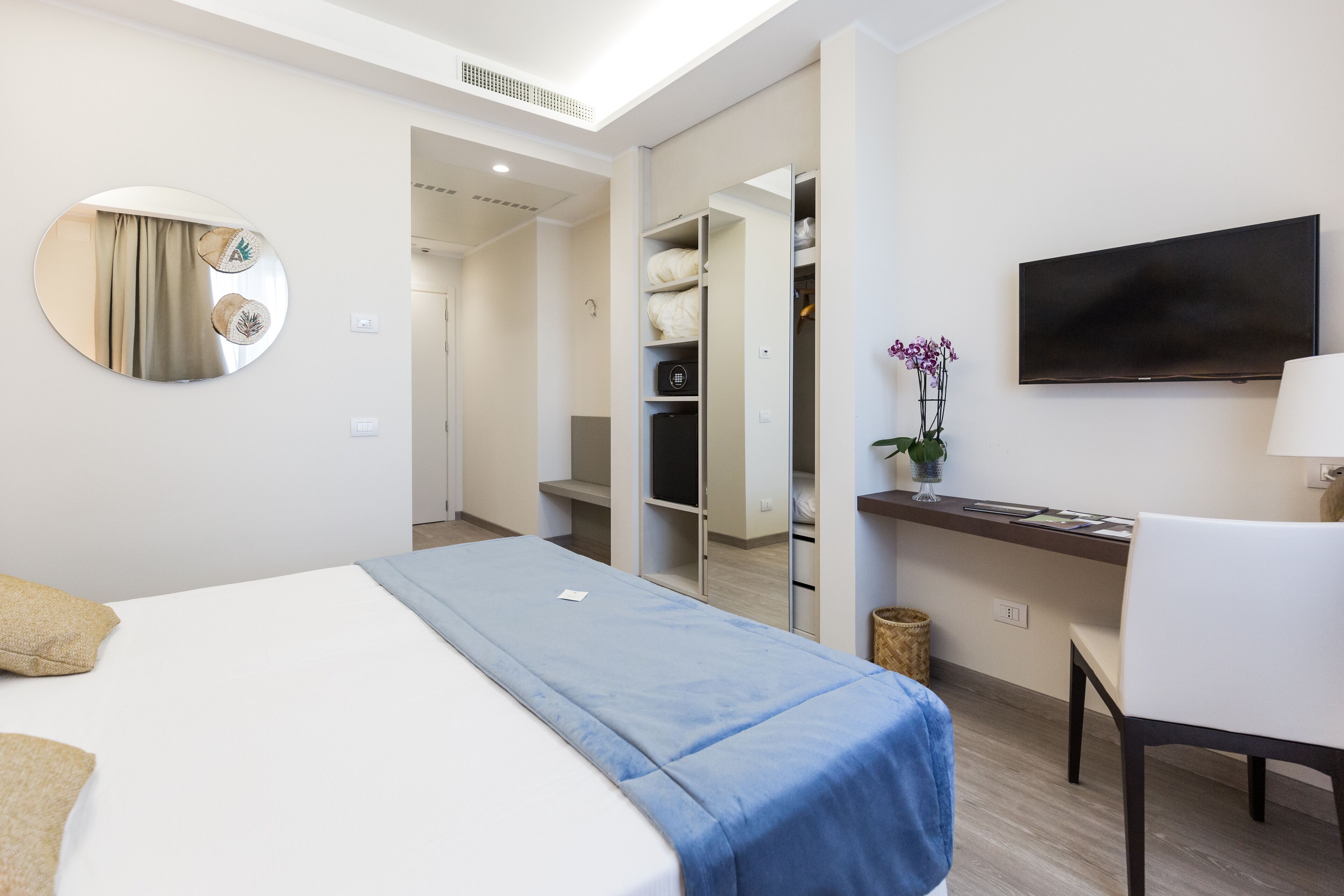 Une chambre d’hôtel équipée d’un lit, d’un bureau, d’une télévision et d’une armoire.