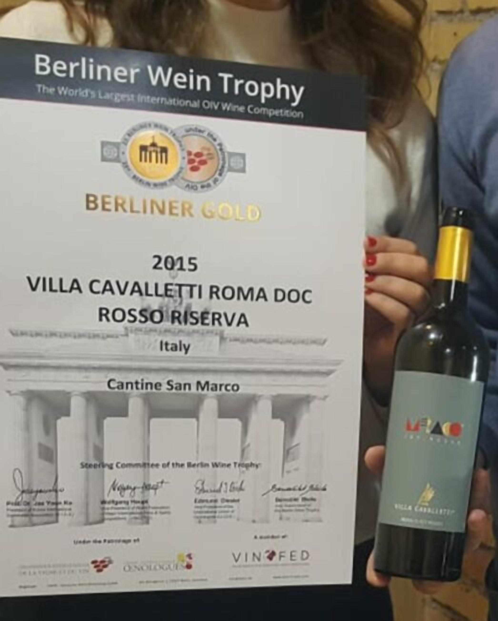 A wine bottle with a label and a certificate for the 2015 Berliner Wein Trophy, indicating a gold award for Villa Cavalletti Roma DOC Rosso Riserva from Italy.