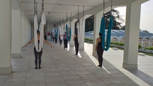 A covered outdoor area with people practicing aerial yoga. - Villa Cavalletti (Grottaferrata)