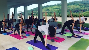 A group of people performing yoga in a covered outdoor area with a scenic view of hills in the background. - Villa Cavalletti (Grottaferrata)