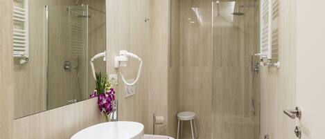 Un baño moderno con un espejo grande, un lavabo redondo, un bidé y una zona de ducha.