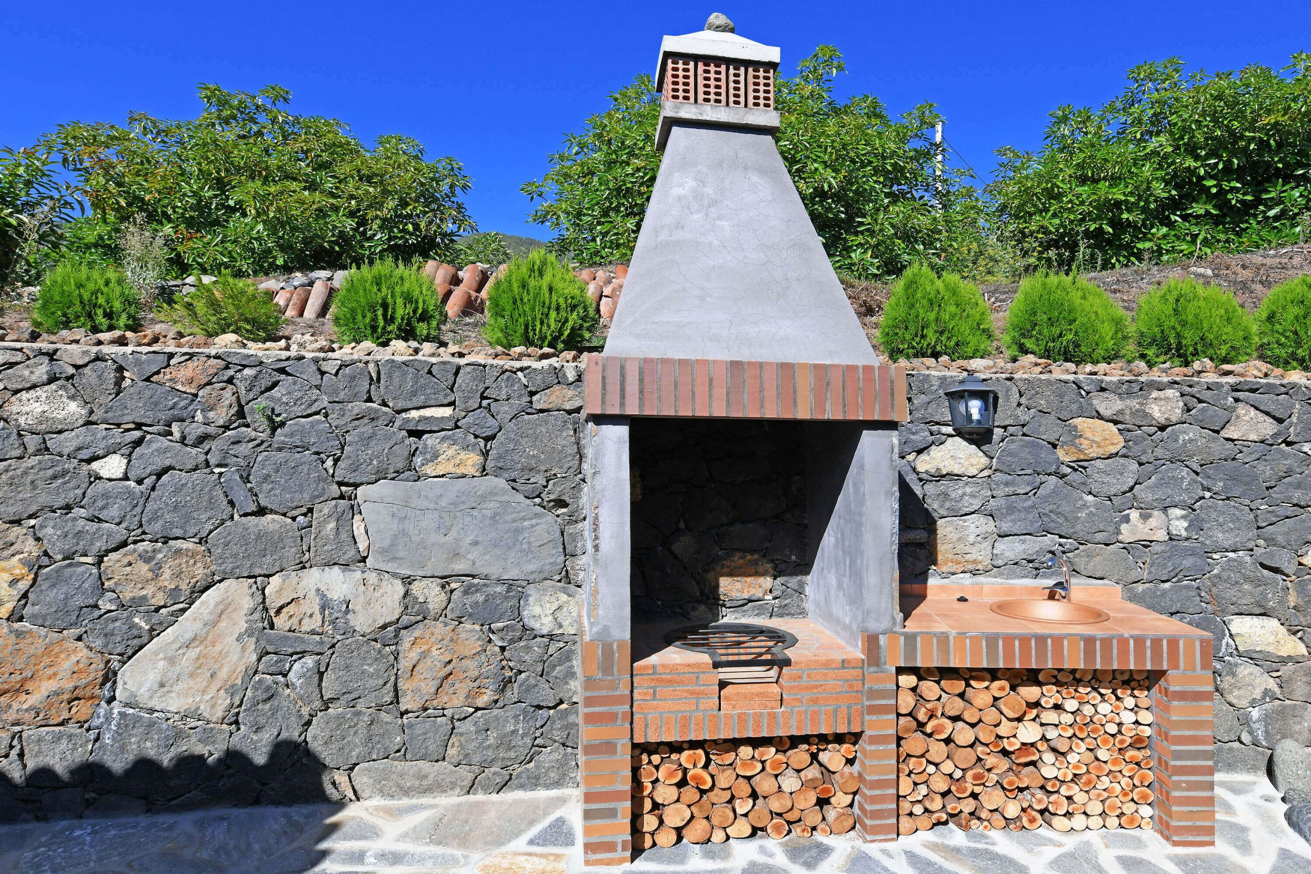 Un mur de pierres avec une structure de four en briques, un foyer et un escalier en pierre.