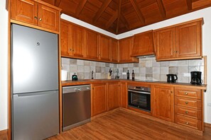 Eine Küche mit Holzschränken, Edelstahlgeräten und einer gefliesten Spritzschutzwand.