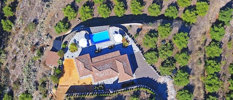 Vue aérienne d’un complexe hôtelier doté d’une piscine, de plusieurs bâtiments et d’un environnement verdoyant.