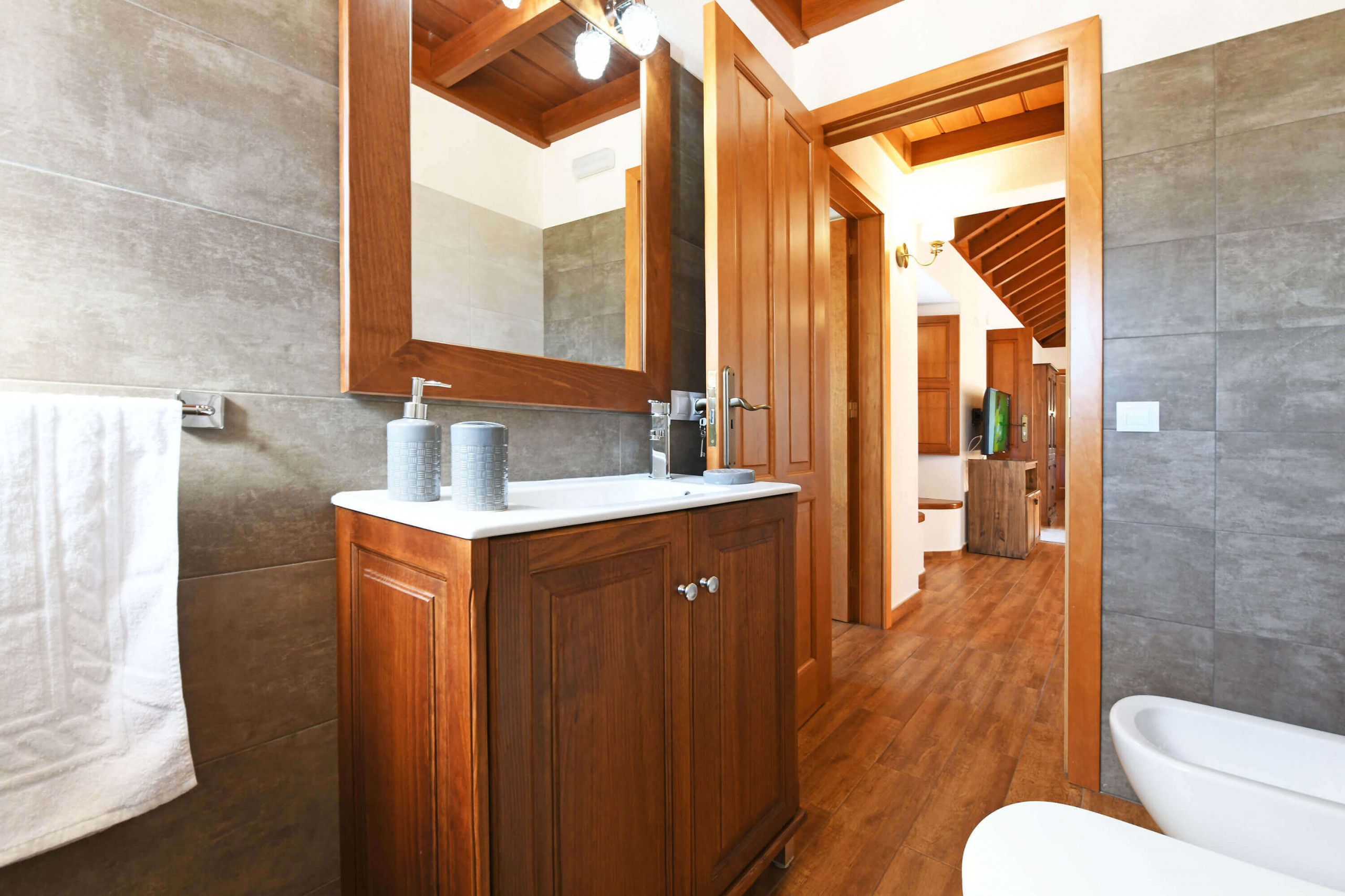 Une salle de bain moderne avec un meuble-lavabo en bois, un grand miroir et une baignoire blanche.