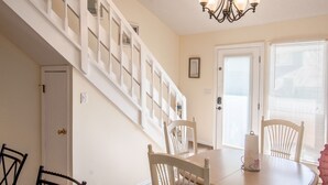 A dining area with a table, chairs, a chandelier, and a staircase. - Cozy beach townhouse within walking distance to the beach. (Miramar Beach)