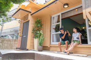 Uma casa com varanda, um vaso de planta e uma janela.