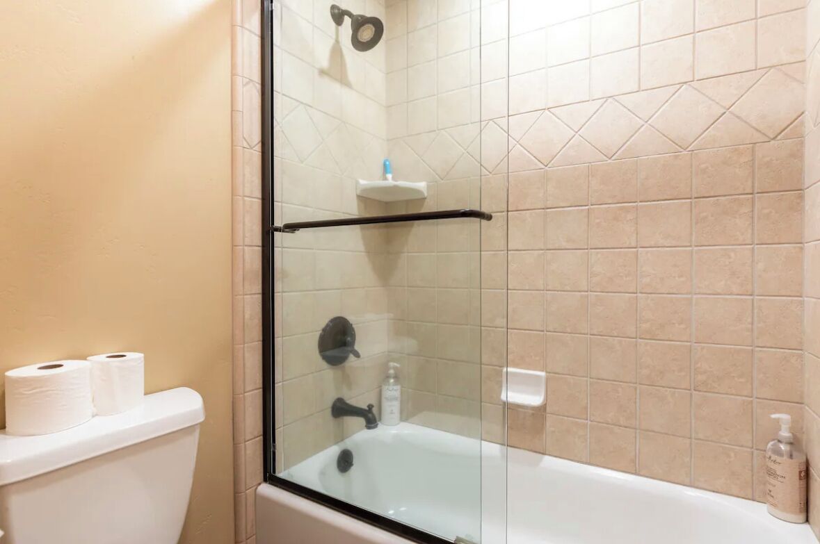 Een badkamer met een douchecabine, een wit toilet en een witte badkuip.