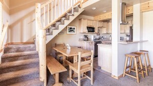 Una cocina moderna con armarios de madera, una isla central y un comedor con mesa y sillas de madera.