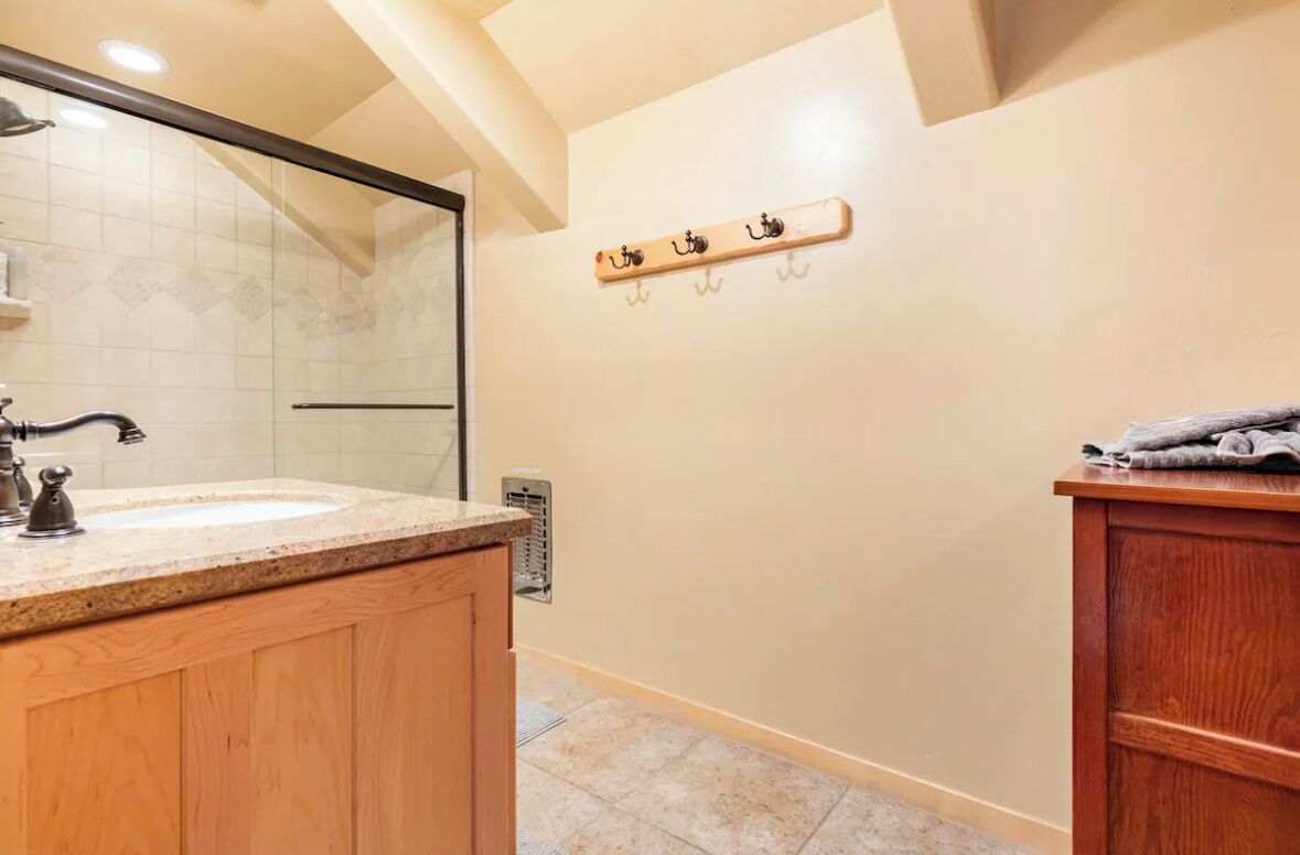 Une salle de bain avec un meuble-lavabo en bois, un évier, un miroir et un porte-serviettes fixé au mur.
