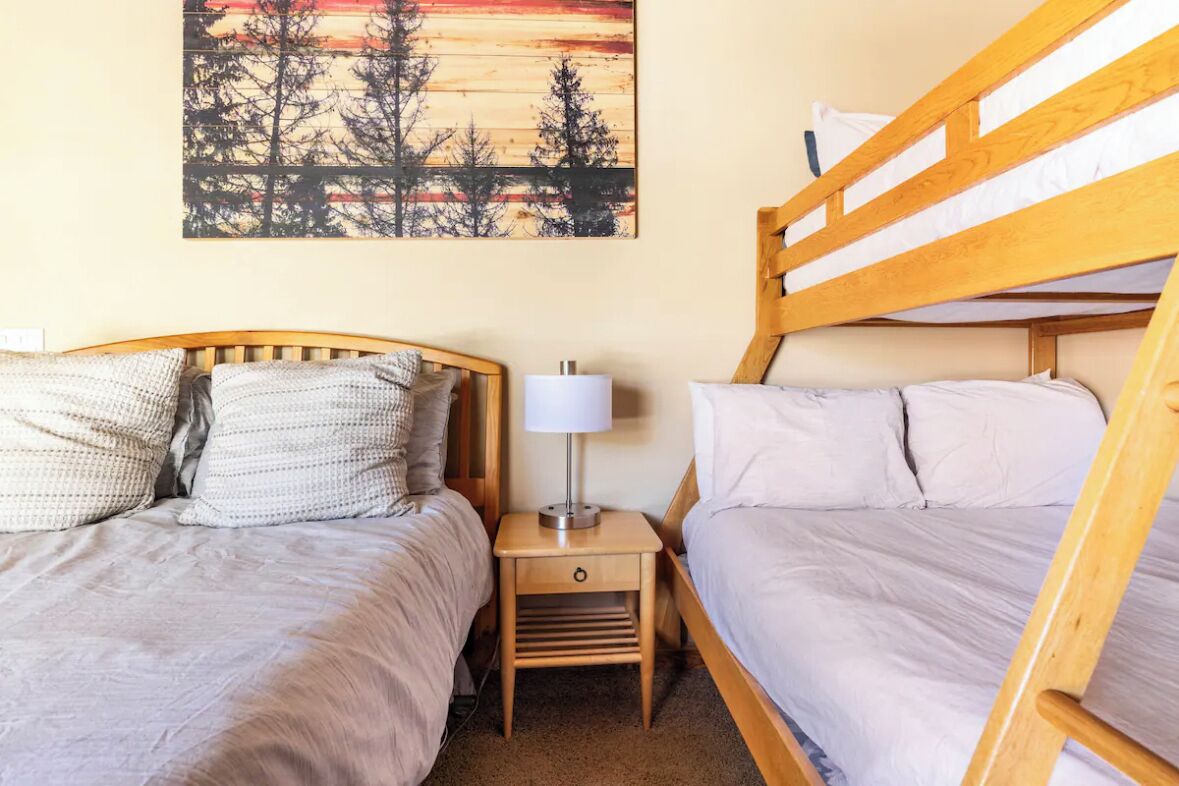 A bedroom with two beds, a nightstand with a lamp, and a painting on the wall.
