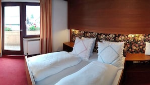 A hotel room with a bed, a desk with a chair, a TV, and a window with curtains. - Sportpension Christina (Fuegen)