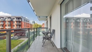Un balcon doté d’une balustrade en verre, d’une table et de deux chaises.