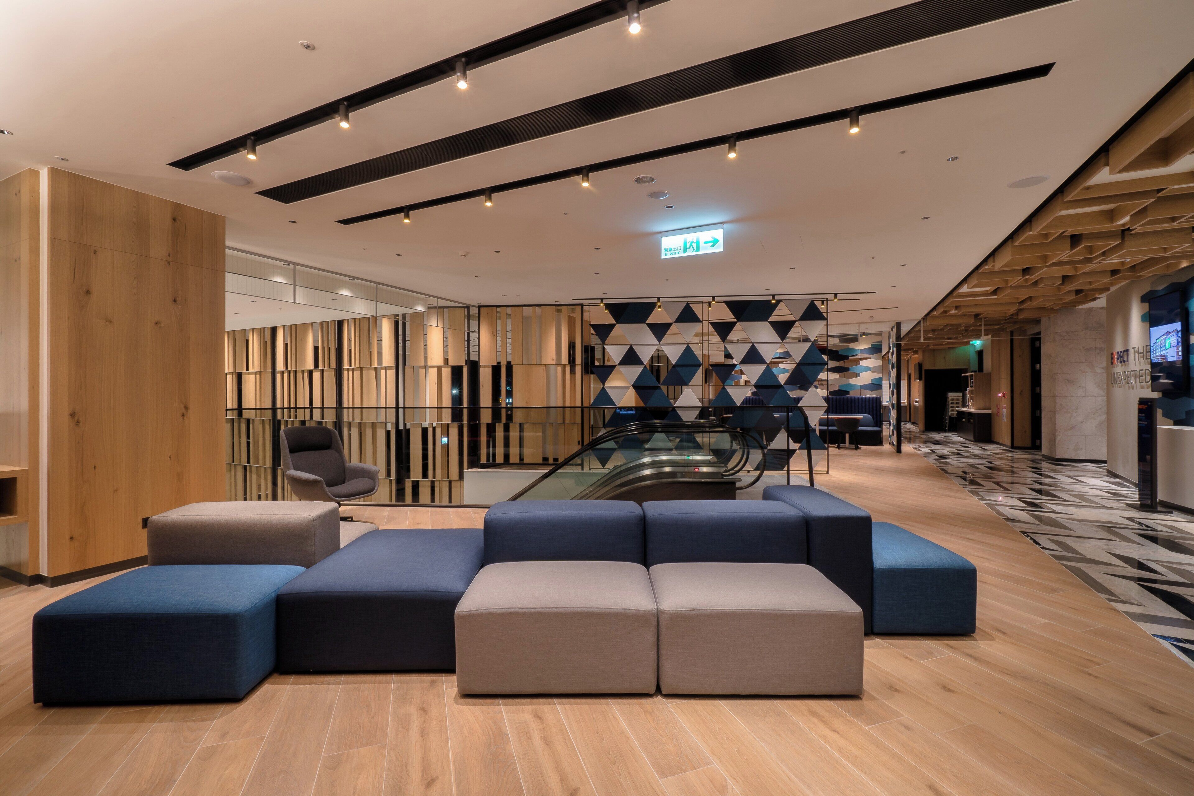 A modern lobby with a seating area, wooden panel walls, and a patterned floor.
