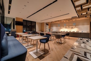A modern dining area with tables and chairs, a kitchen counter, and a seating area with a sofa. - Holiday Inn Express Chiayi by IHG (Chiayi City)