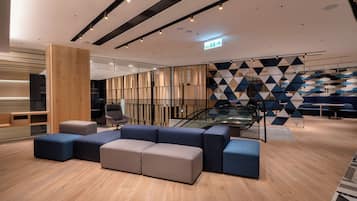 A modern lobby with a seating area, a staircase, and a geometric patterned wall.